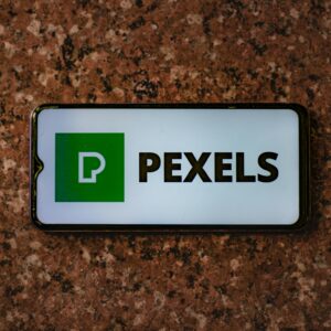 A smartphone displaying the Pexels app logo on a granite tabletop.